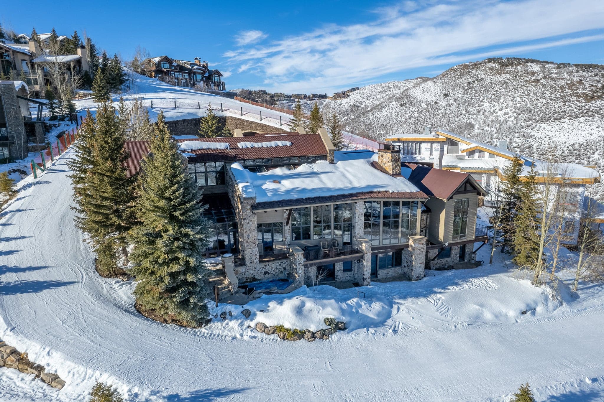 Aerial view of luxury ski-in/ski-out home with snow-covered roof and mountain backdrop