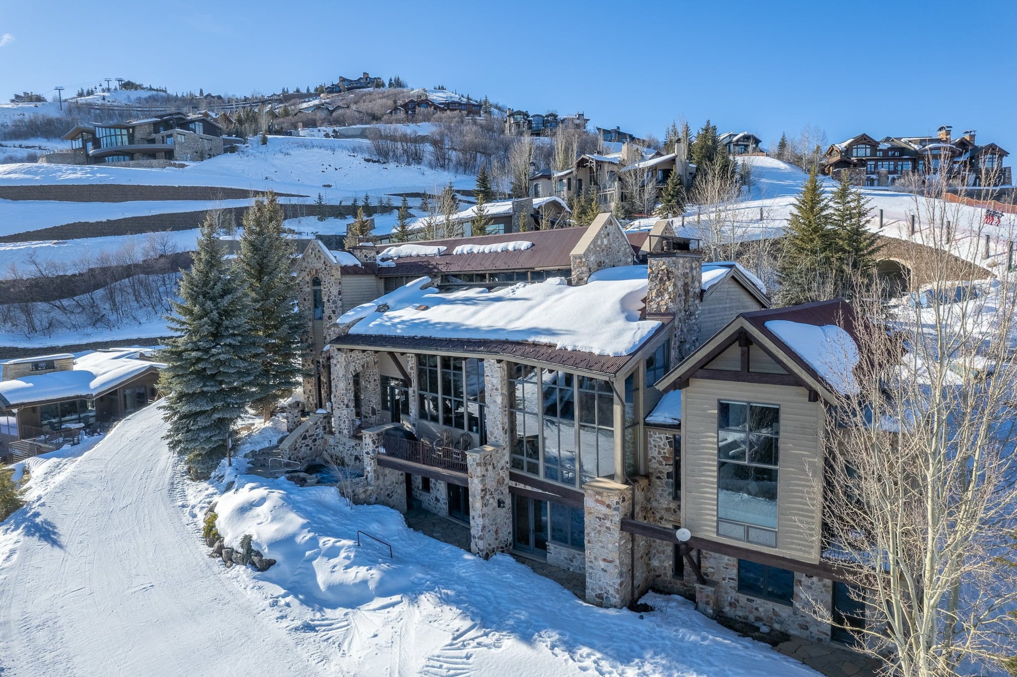 An angled view of the exterior of this luxury Park City rental property, showing the trees and mountains around the home.