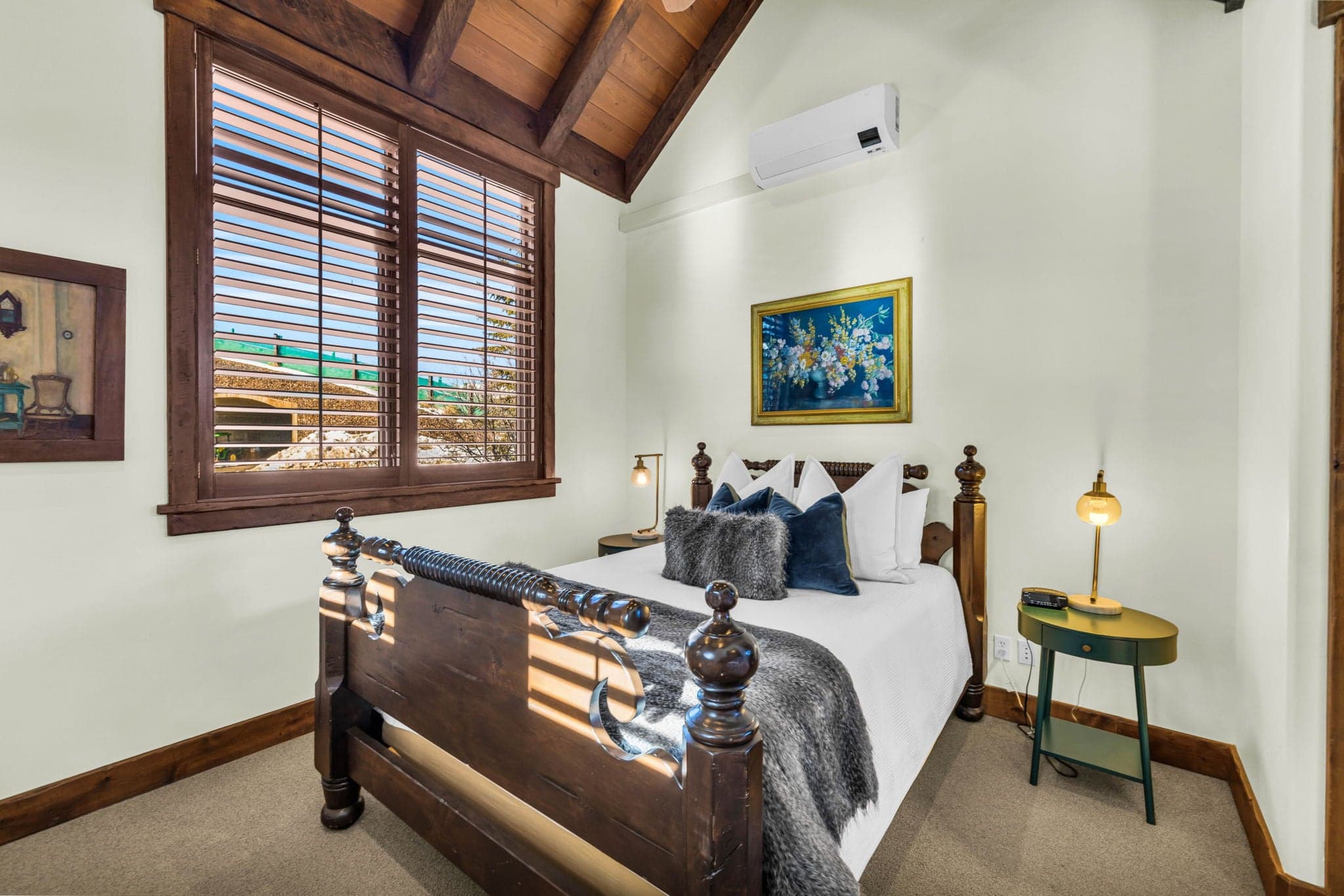 Cozy guest bedroom with wood accents, queen bed, and decorative artwork.