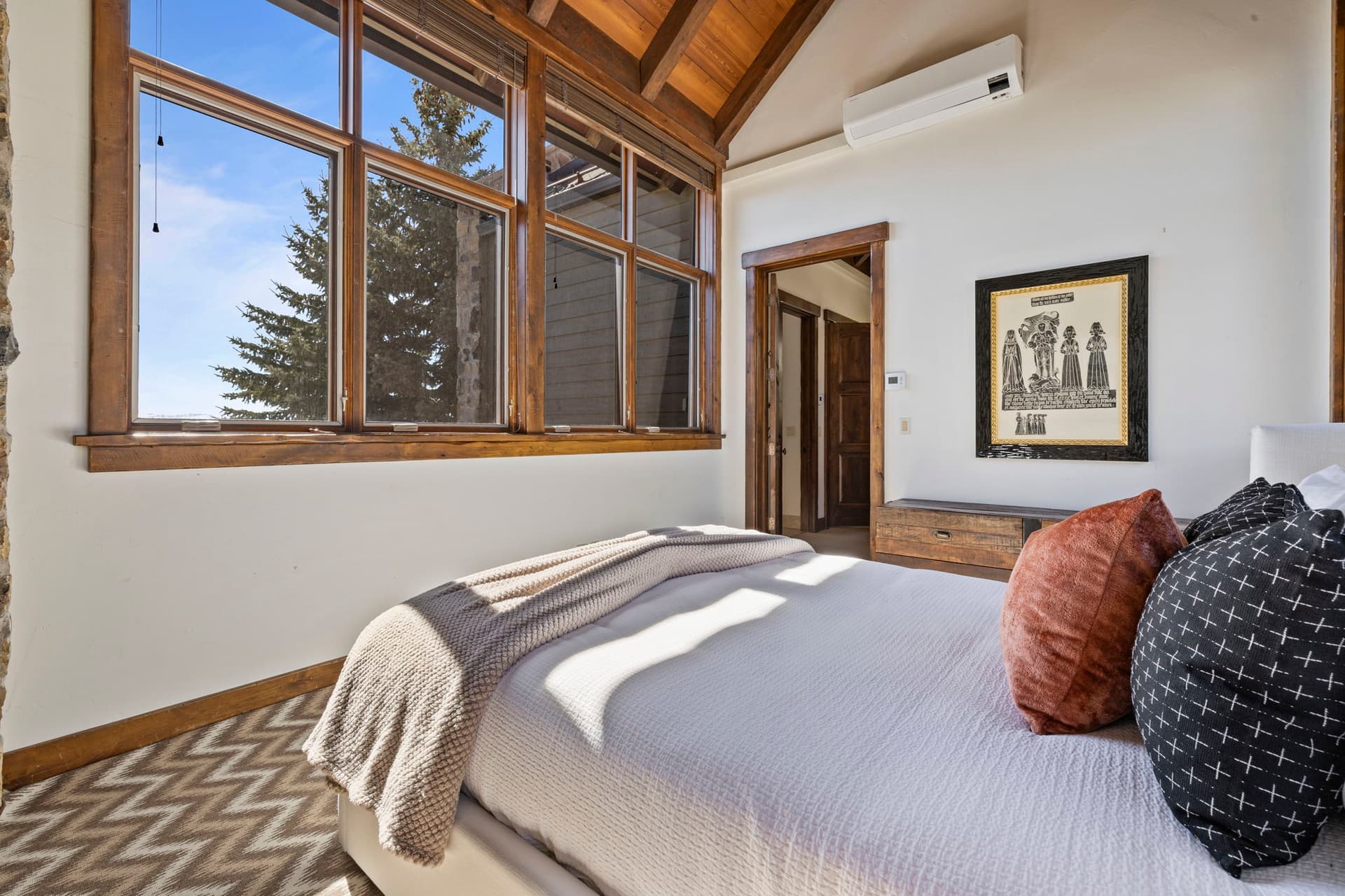 Guest bedroom with large windows framing mountain views and rustic decor.