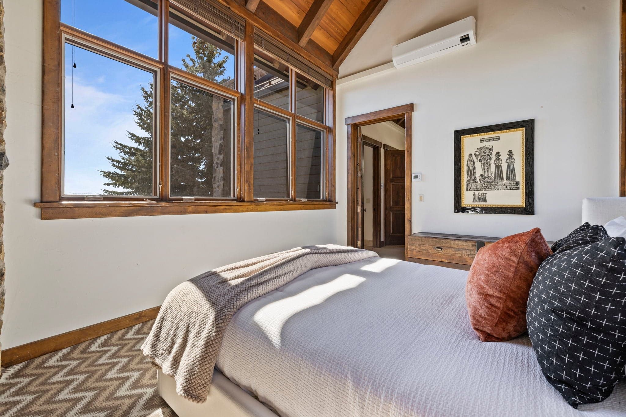 Guest bedroom with large windows framing mountain views and rustic decor.