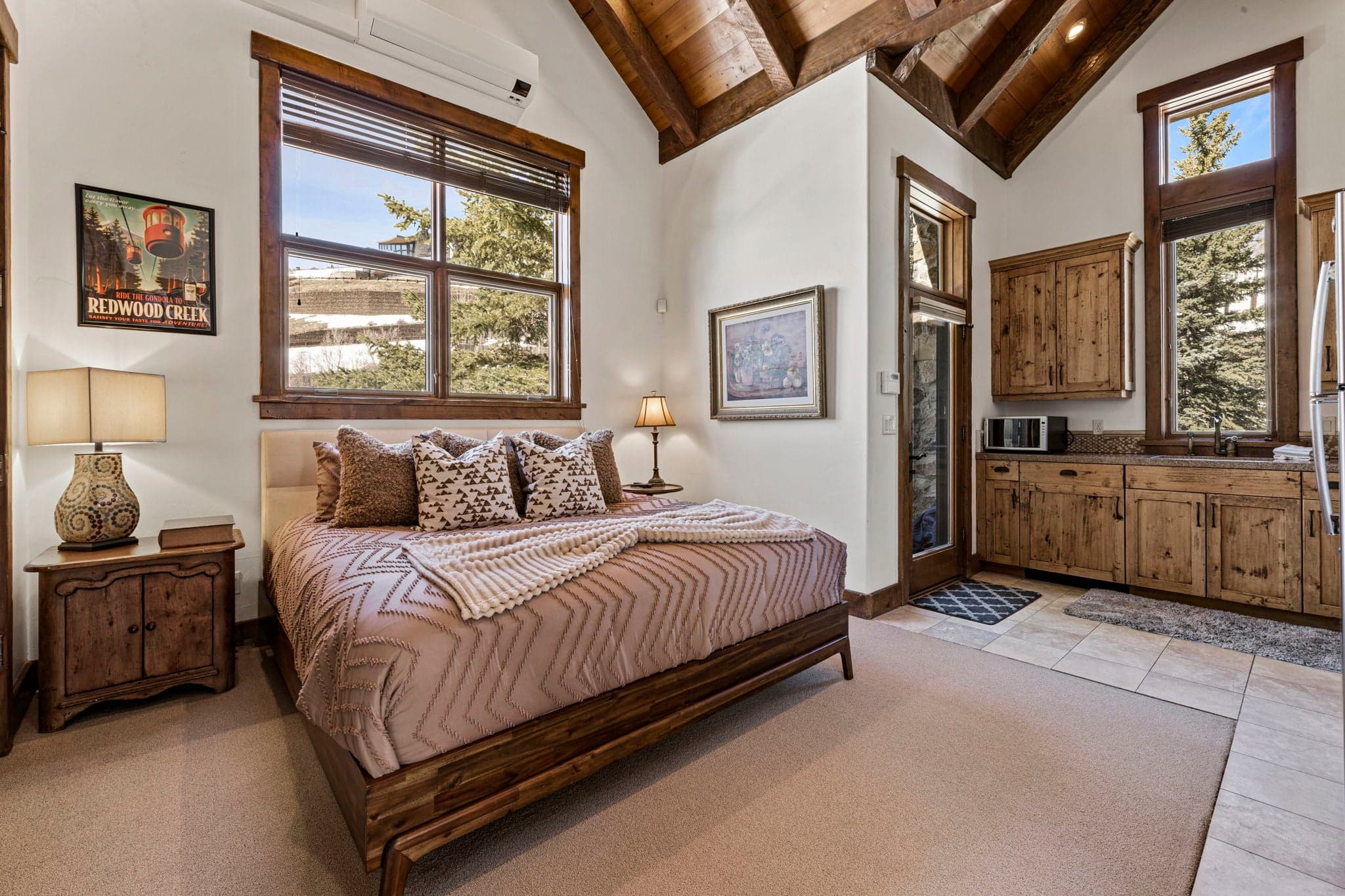 Bedroom with wood furnishings, plush bedding, and kitchenette.