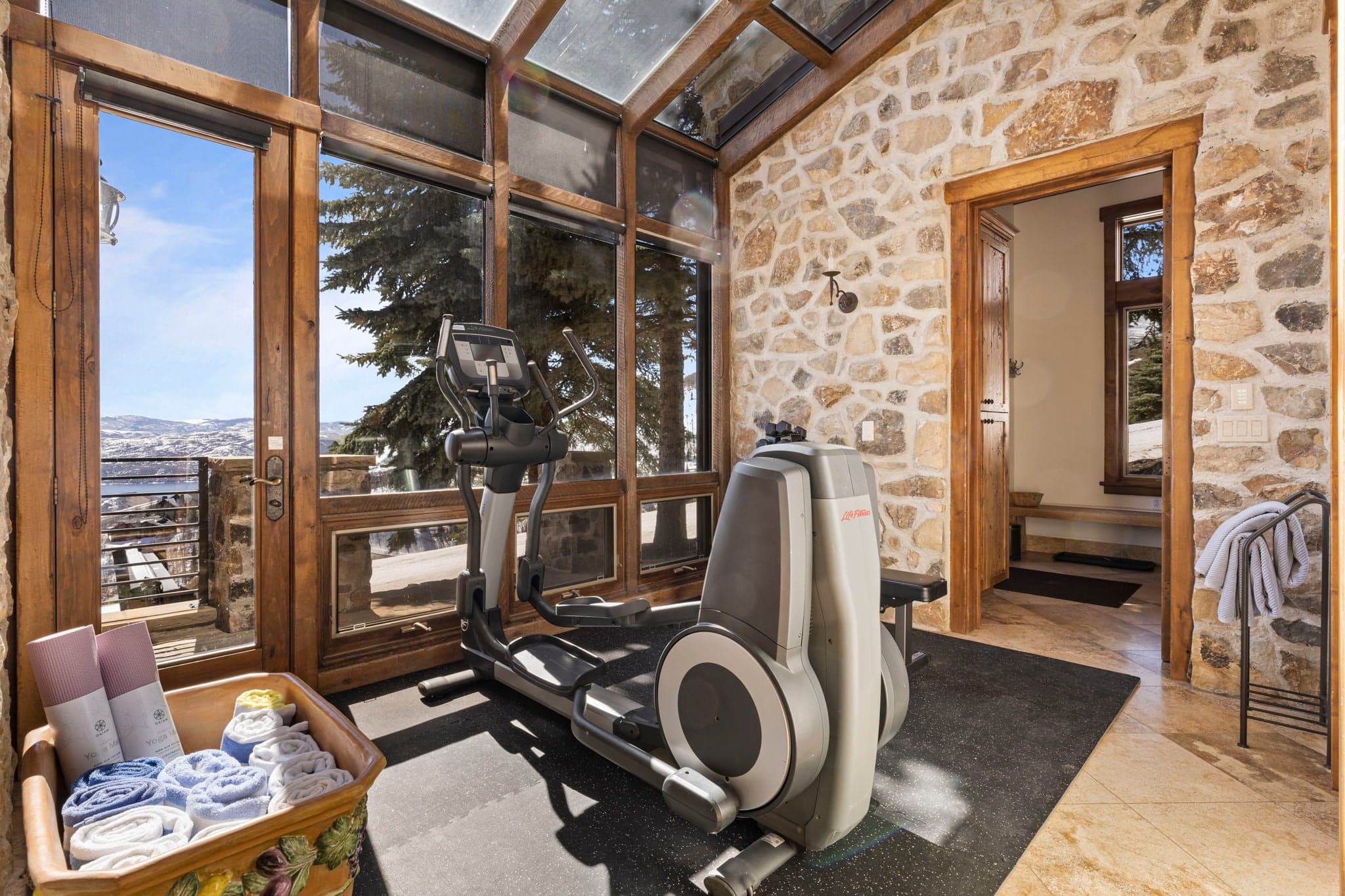 Home gym with exercise bike and floor-to-ceiling windows overlooking mountain views.