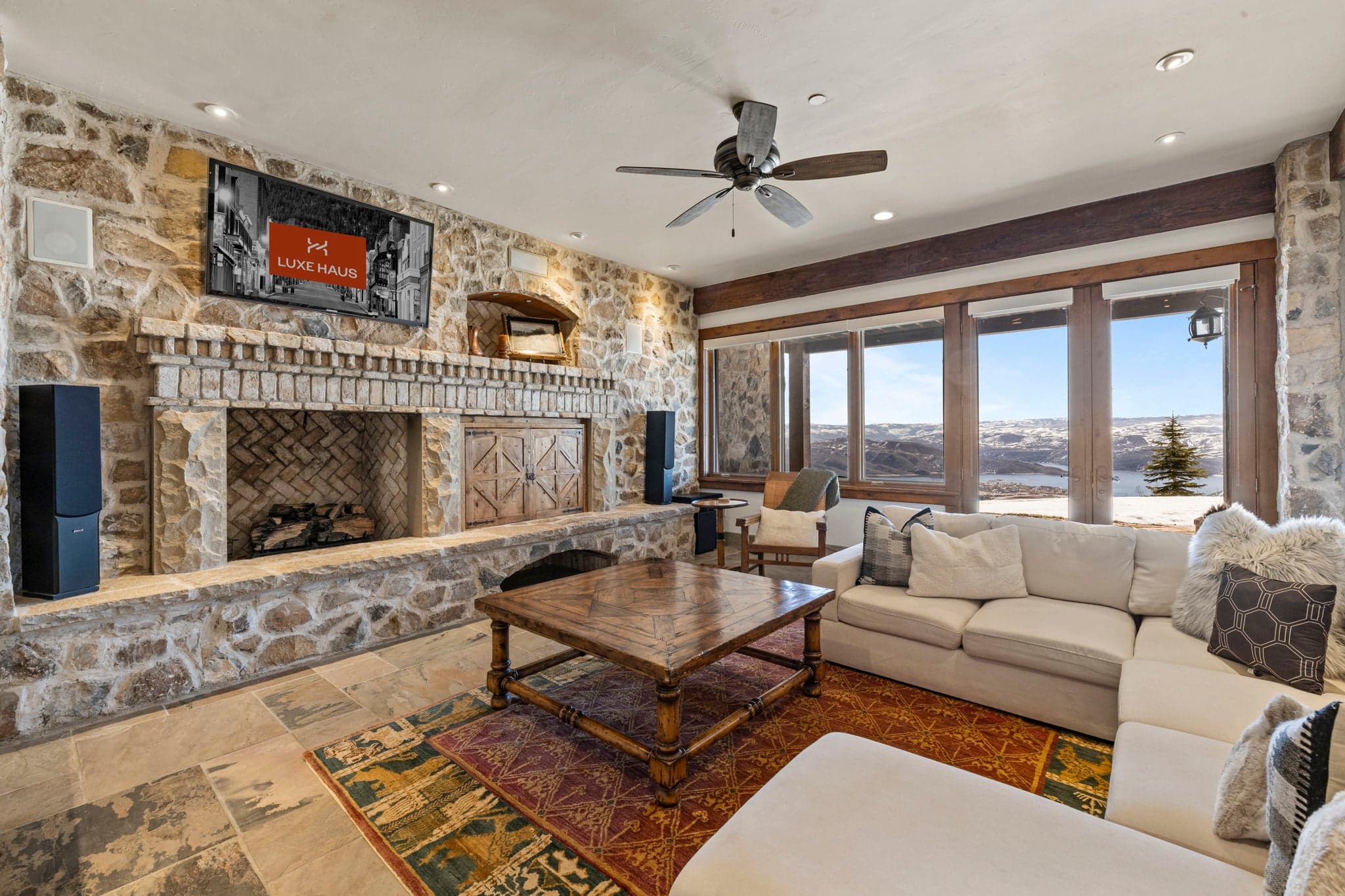 Living space with sectional sofa, stone fireplace, and walk-out patio views