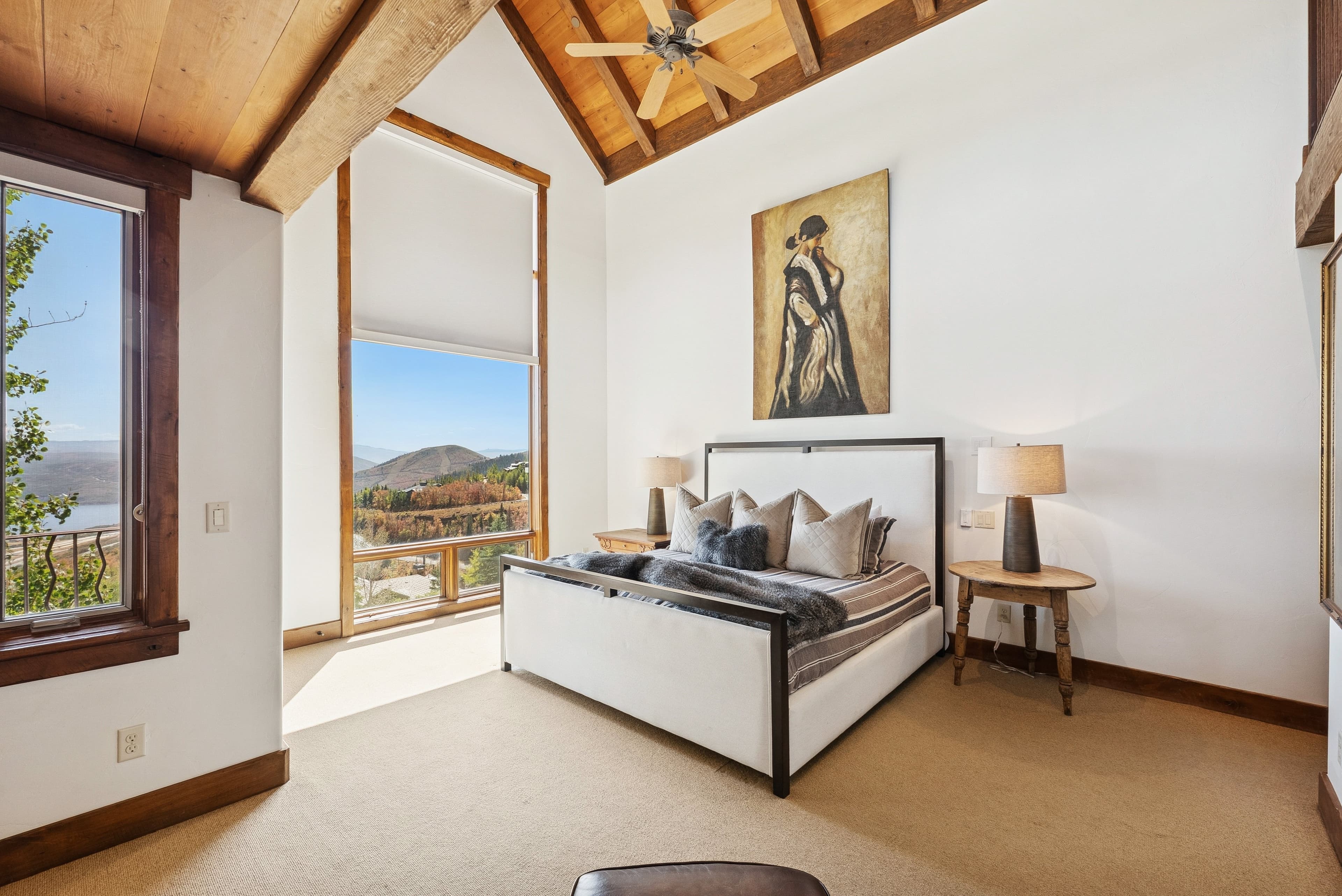 Bedroom with upholstered bed, modern artwork, and balcony doors opening to mountain views.