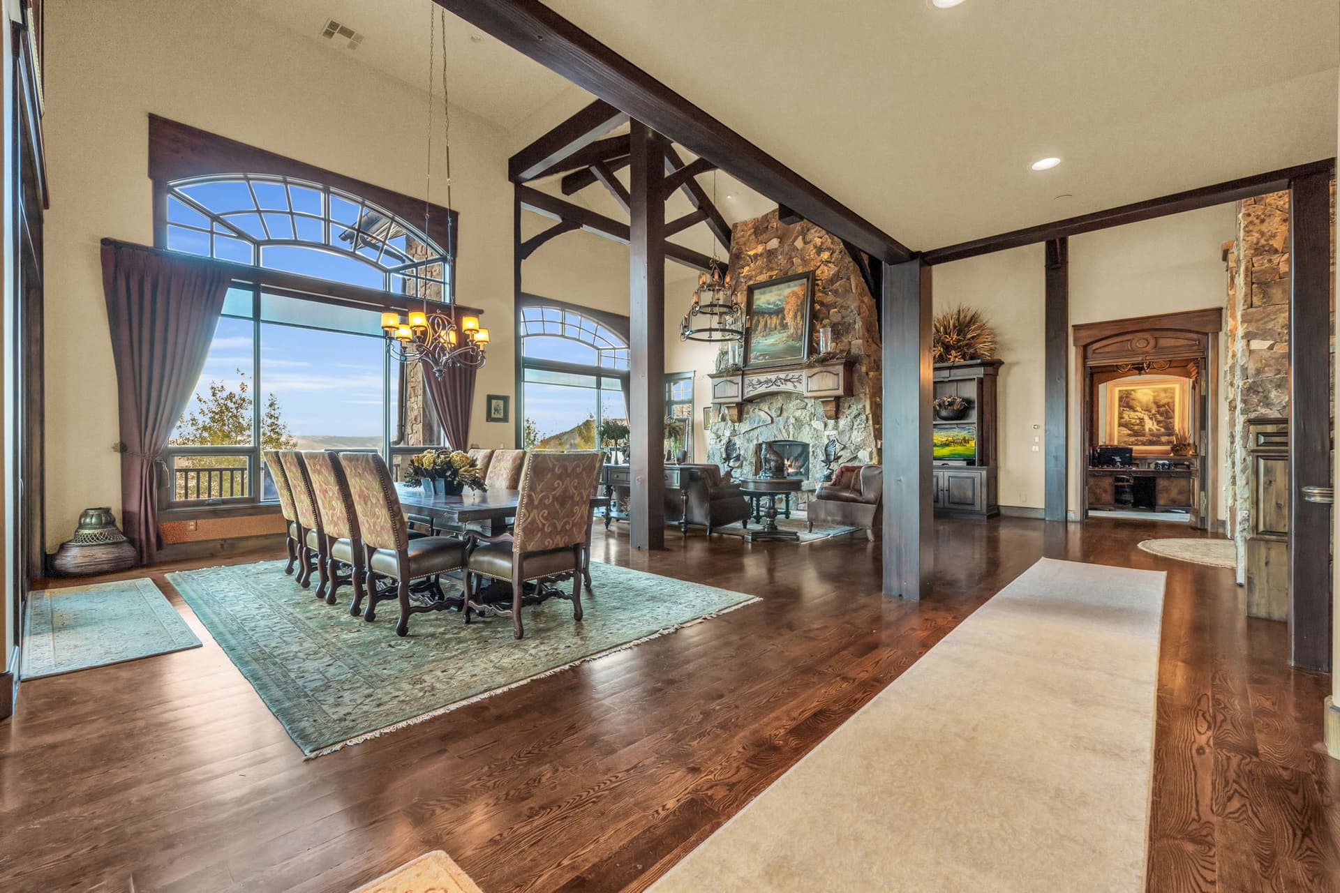Spacious living room  with paintings, chandelier, dining room, and fireplace.