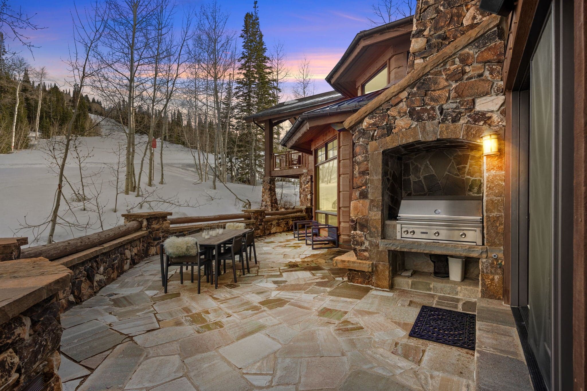 Stunning outdoor grill area next to the slopes with dining table and lighting