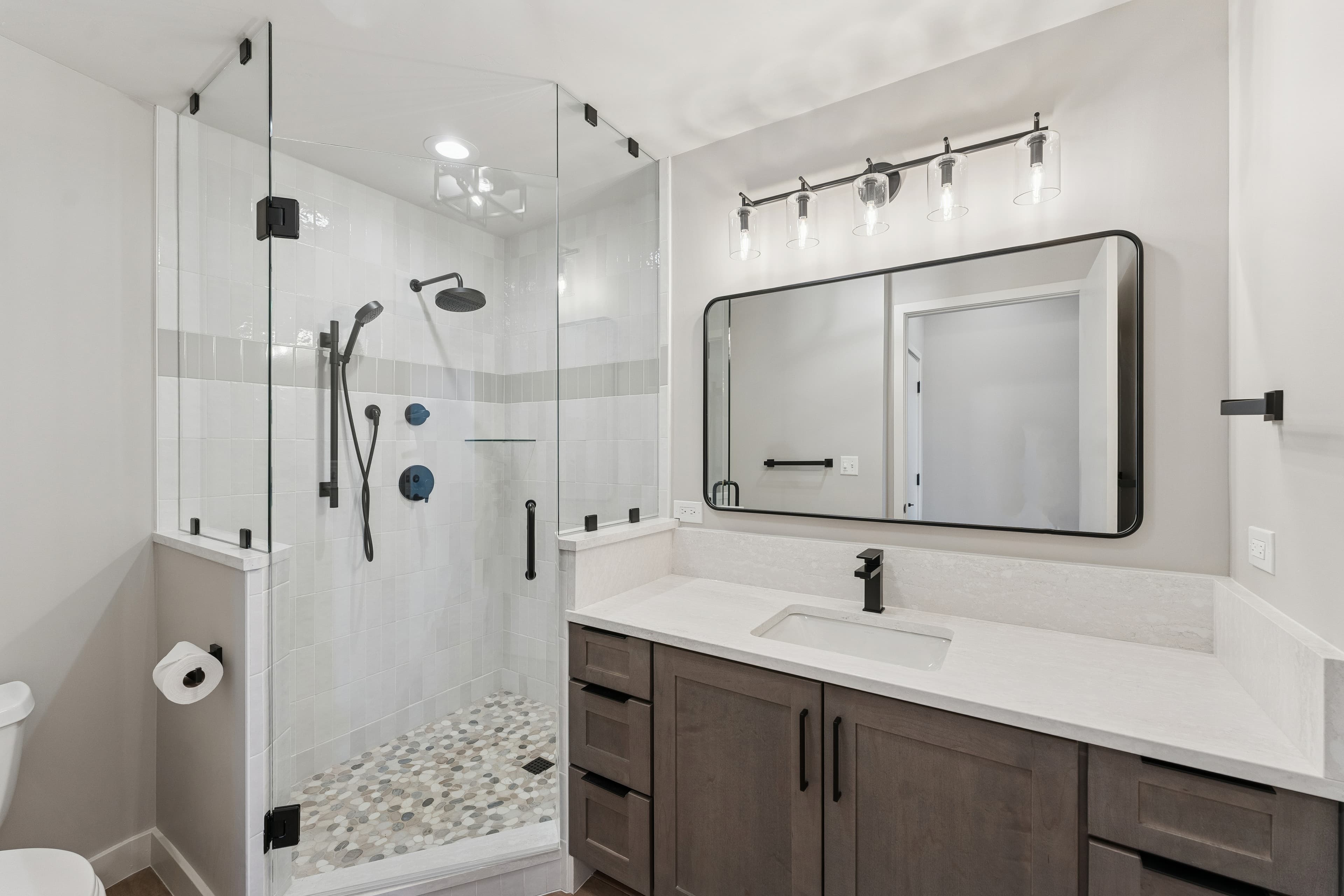Sleek bathroom with glass-enclosed shower, large vanity, and contemporary lighting.